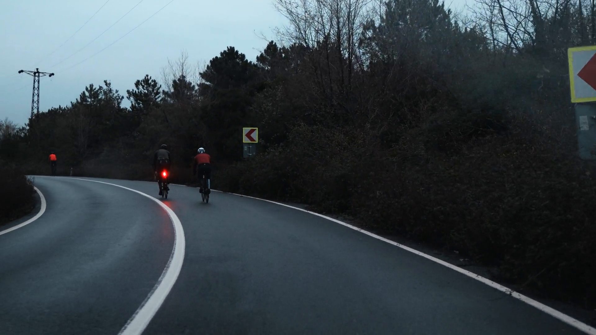 Cyclists riding a path under a bridge in golden light